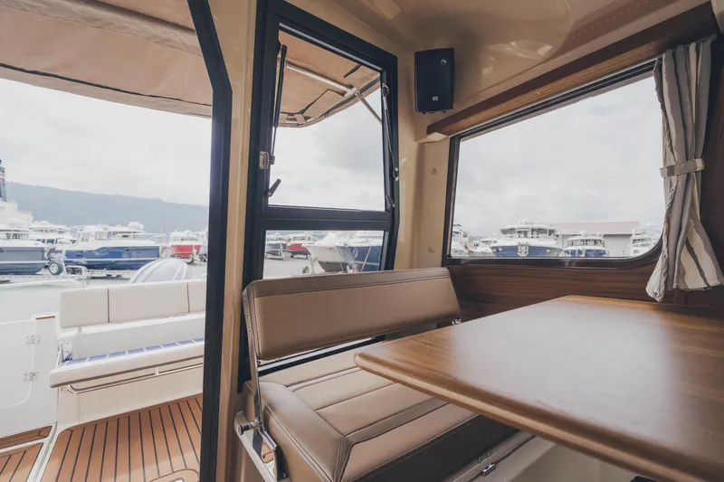  Yacht Photos Pics Interior of 2025 Ranger Tugs R-23 boat, featuring seating and table with marina view.