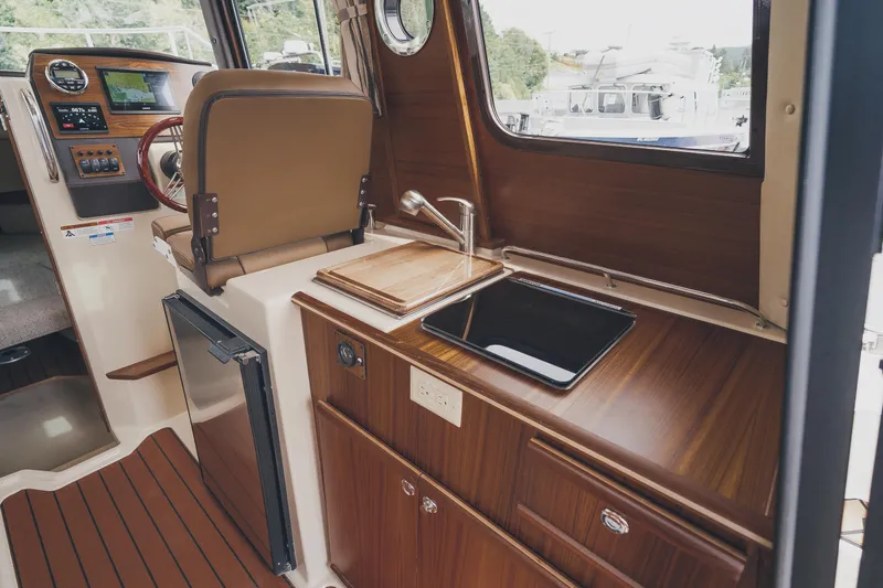  Yacht Photos Pics 2025 Ranger Tugs R-23 interior with kitchenette, featuring wood cabinetry and modern appliances.