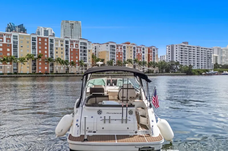  Yacht Photos Pics 2015 Sea Ray 350 Sundancer yacht on water, cityscape background, clear blue sky.