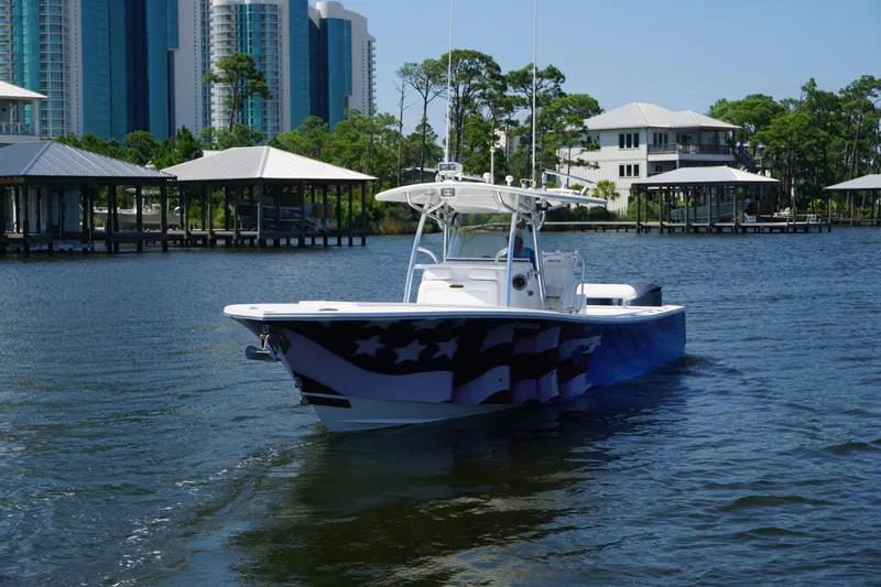 Past Time Yacht Photos Pics 2012 Regulator 32 Forward Seating boat on water, with American flag design, near waterfront buildings.