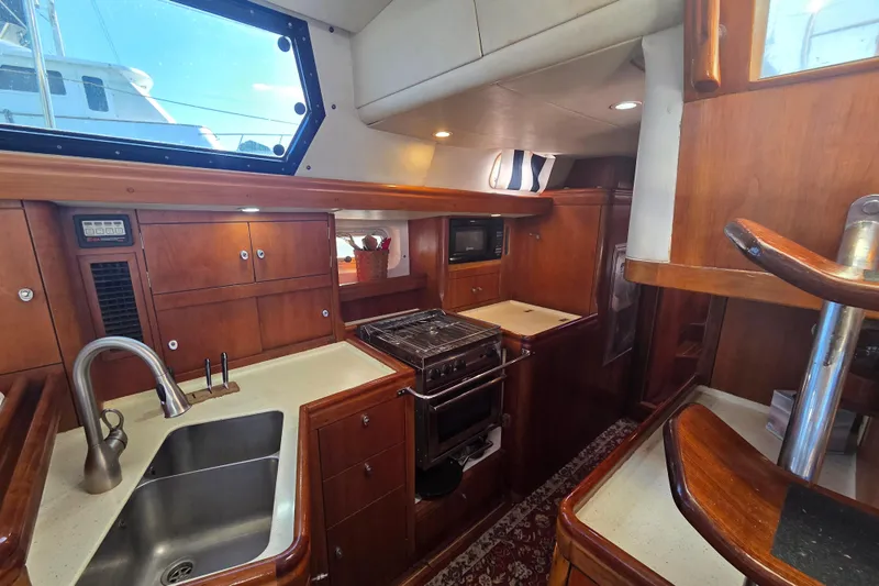 Pemaquid Yacht Photos Pics Interior of 1998 Oyster 485 Deck Saloon yacht with wooden cabinetry and modern kitchen amenities.