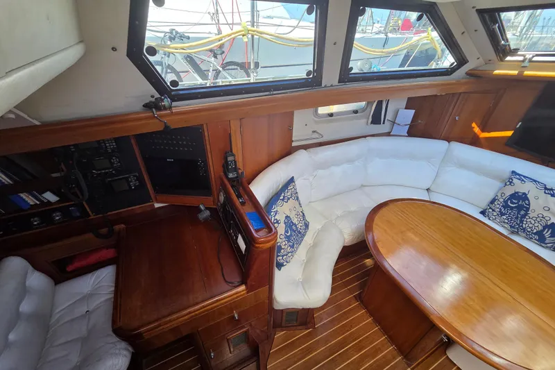 Pemaquid Yacht Photos Pics Luxurious interior of 1998 Oyster 485 Deck Saloon with white seating and wooden table.