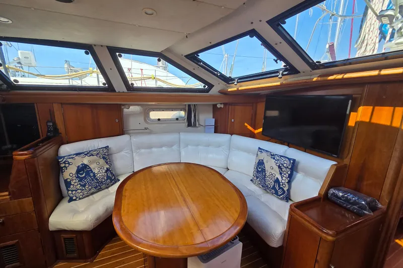 Pemaquid Yacht Photos Pics Luxurious interior of 1998 Oyster 485 Deck Saloon yacht with white seating and wooden table.