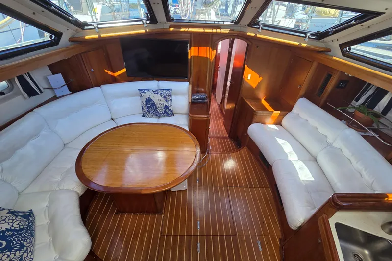 Pemaquid Yacht Photos Pics Luxurious interior of 1998 Oyster 485 Deck Saloon with white seating and wooden accents.