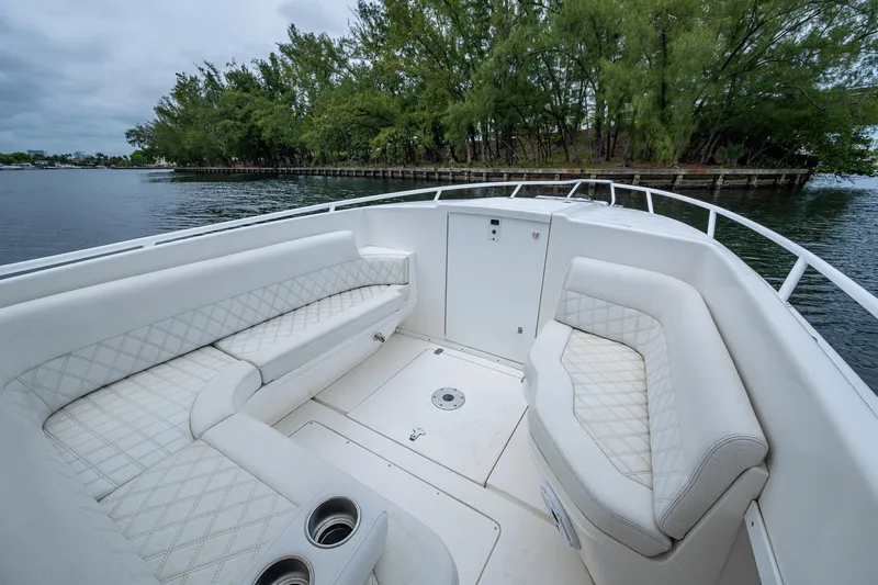  Yacht Photos Pics 2003 Intrepid 32 boat interior with white seating, near lush green island.