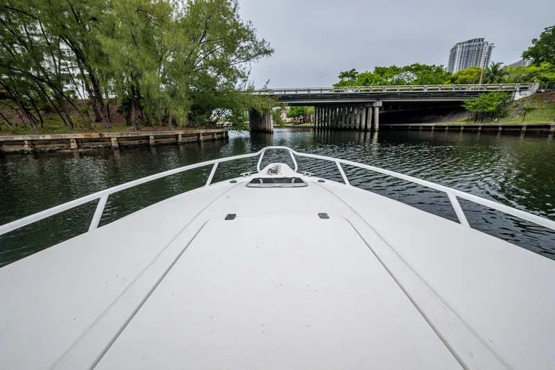  Yacht Photos Pics Bow view of 2003 Intrepid 32 boat navigating a calm waterway under a bridge.