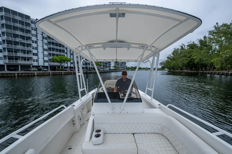  Yacht Photos Pics 2003 Intrepid 32 boat cruising on a canal with modern buildings and trees in the background.