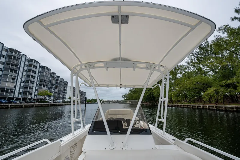  Yacht Photos Pics 2003 Intrepid 32 boat navigating a canal with modern buildings and trees in the background.