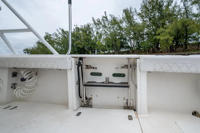  Yacht Photos Pics 2003 Intrepid 32 boat interior with open storage compartment and lush greenery in the background.