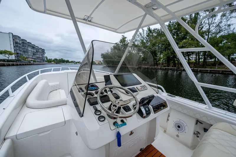  Yacht Photos Pics 2003 Intrepid 32 boat cockpit with steering wheel, navigation controls, and waterfront view.