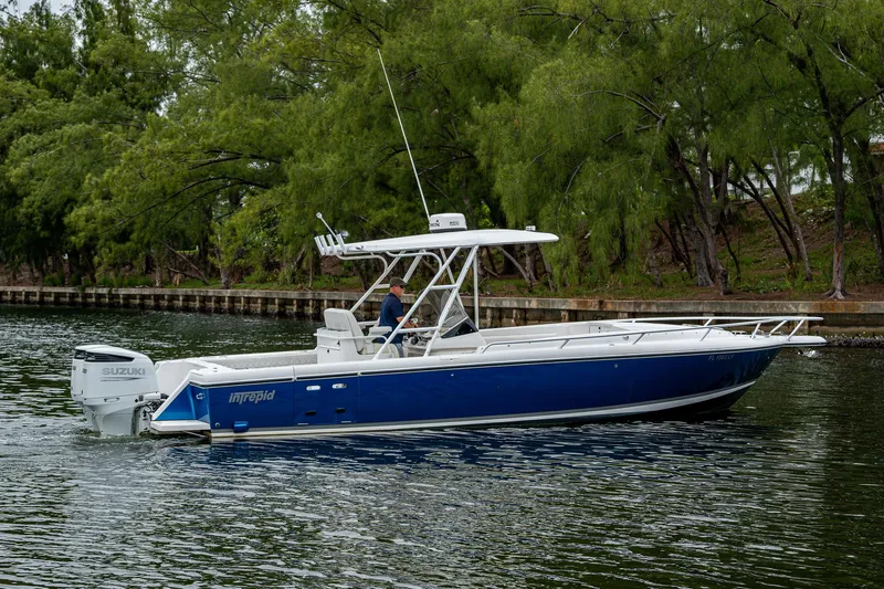  Yacht Photos Pics 2003 Intrepid 32 boat cruising on a calm waterway, surrounded by lush greenery.