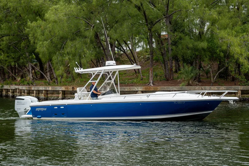  Yacht Photos Pics 2003 Intrepid 32 boat cruising on a calm waterway, surrounded by lush greenery.
