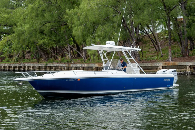  Yacht Photos Pics 2003 Intrepid 32 boat cruising on a calm waterway, surrounded by lush greenery.