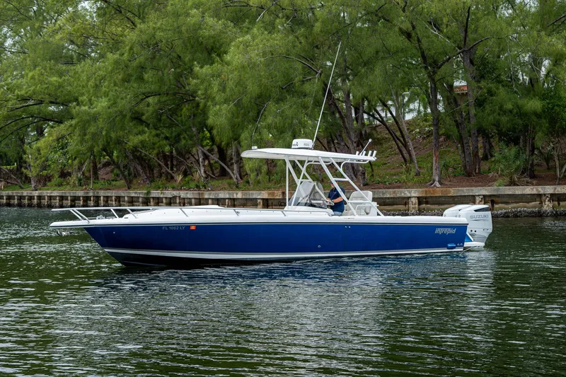  Yacht Photos Pics 2003 Intrepid 32 boat cruising on a calm waterway with lush green trees in the background.