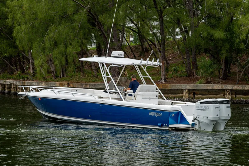  Yacht Photos Pics 2003 Intrepid 32 boat with blue hull cruising on a calm waterway.