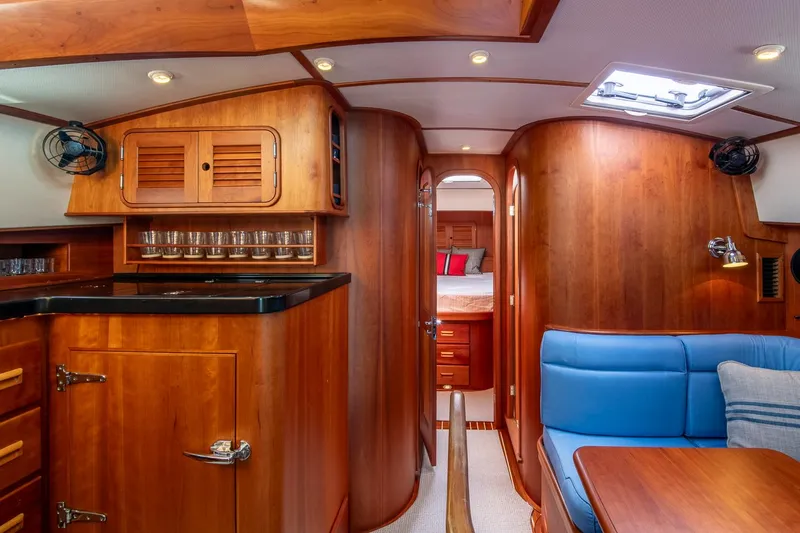 Halcyon Yacht Photos Pics Luxurious interior of 2006 Hinckley Talaria 44 FB yacht with wood finish and blue seating.