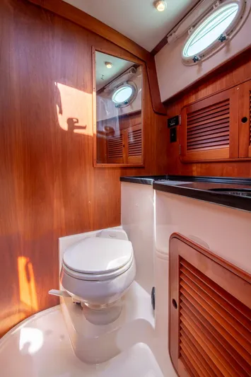 Halcyon Yacht Photos Pics 2006 Hinckley Talaria 44 FB yacht bathroom with wooden cabinetry and porthole window.