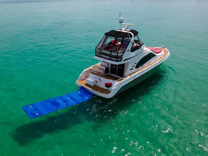  Yacht Photos Pics 2006 Sea Ray 44 Sedan Bridge yacht on turquoise water with blue swim mat.