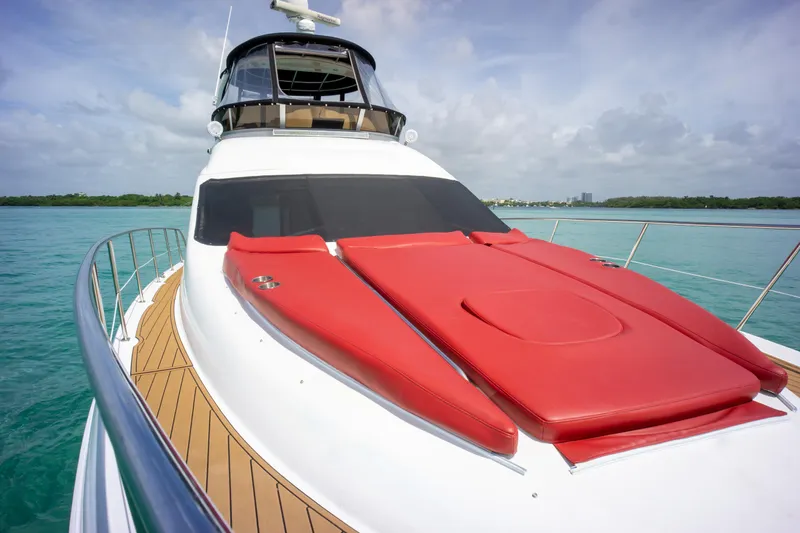  Yacht Photos Pics 2006 Sea Ray 44 Sedan Bridge yacht with red sunbeds on deck, cruising in clear waters.