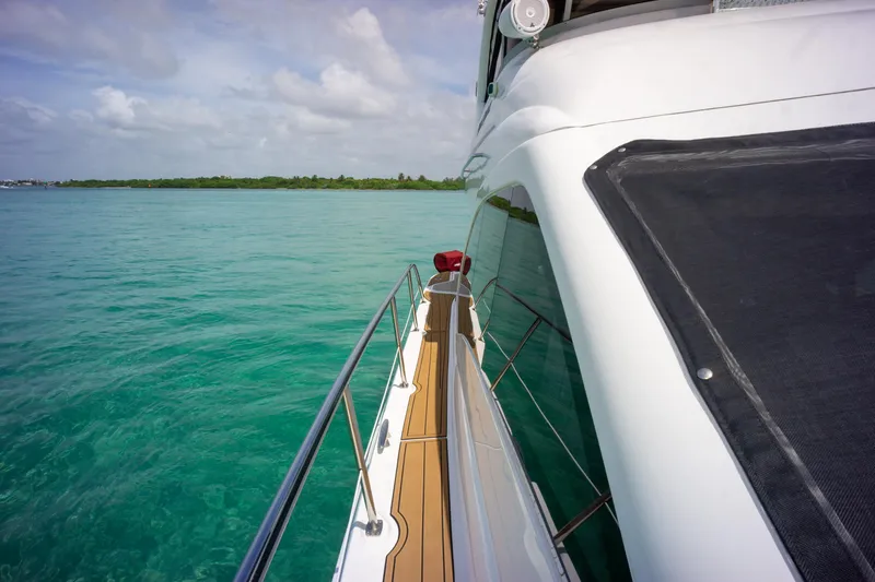  Yacht Photos Pics 2006 Sea Ray 44 Sedan Bridge yacht cruising on turquoise waters under a cloudy sky.