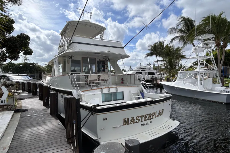 Masterplan Yacht Photos Pics 1975 Hatteras 58 YF yacht docked in Miami, surrounded by palm trees and other boats.