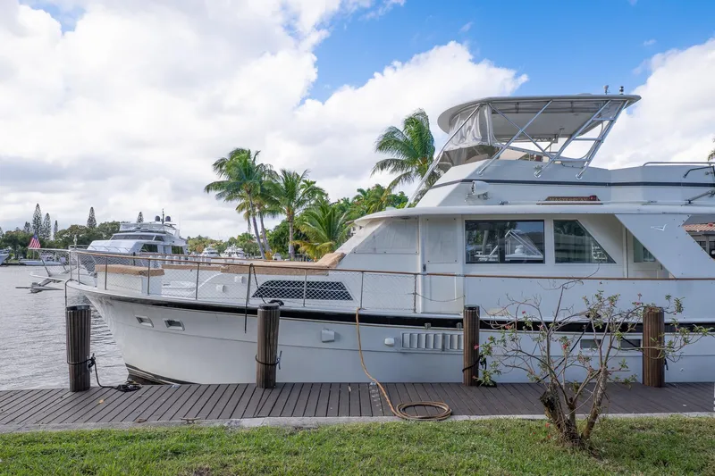 Masterplan Yacht Photos Pics 1975 Hatteras 58 YF yacht docked by palm trees under a cloudy sky.