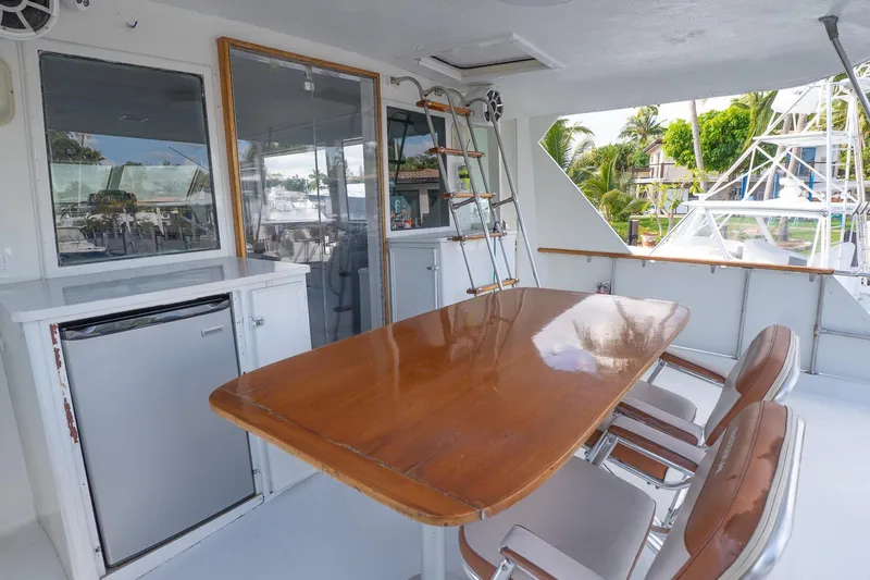 Masterplan Yacht Photos Pics 1975 Hatteras 58 YF yacht deck with wooden table, chairs, and mini fridge.