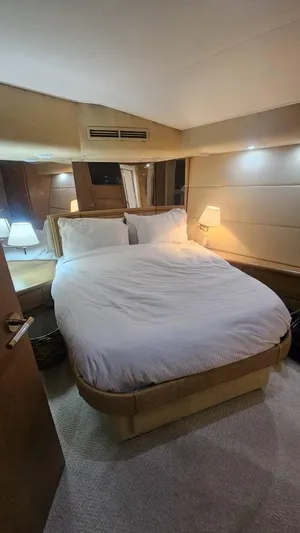  Yacht Photos Pics Luxurious bedroom interior of 1999 Hatteras 65 Convertible yacht with cozy lighting.