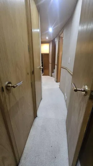  Yacht Photos Pics Hallway inside 1999 Hatteras 65 Convertible yacht with wooden doors and carpeted floor.