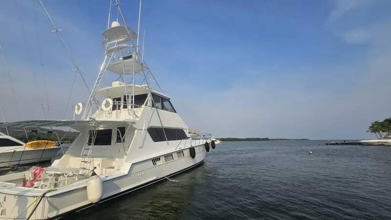  Yacht Photos Pics 1999 Hatteras 65 Convertible yacht docked on calm water under clear blue sky.