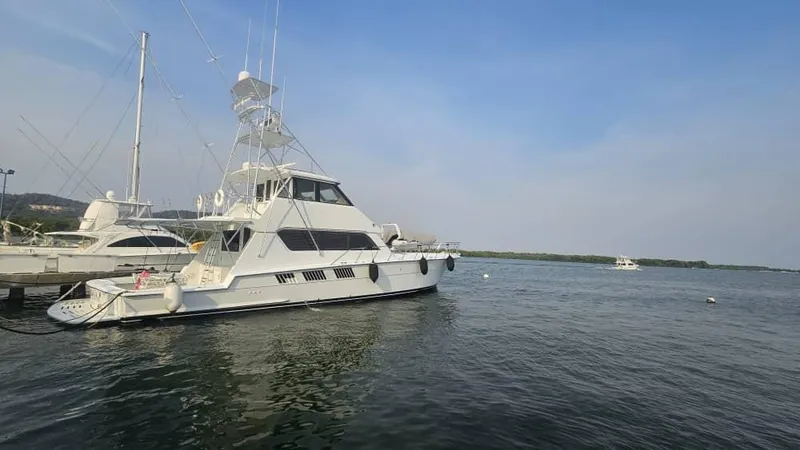  Yacht Photos Pics 1999 Hatteras 65 Convertible yacht docked in calm waters under a clear sky.