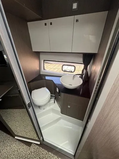 Fortuna Yacht Photos Pics Modern bathroom in 2022 Beneteau 32 Gran Turismo yacht with sink, toilet, and storage cabinets.