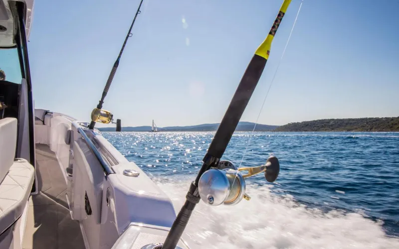  Yacht Photos Pics 2025 Axopar 29 CCX boat with fishing rods on a sunny day at sea.