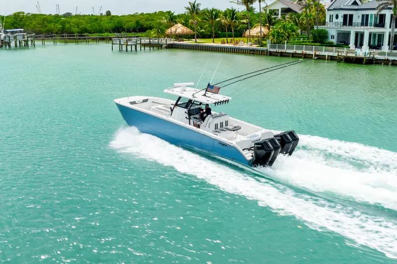 Kroppdustr Yacht Photos Pics 2023 Invincible 37 Catamaran cruising on turquoise water near waterfront homes.