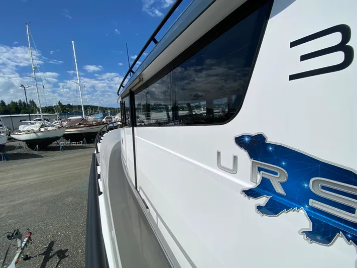 Ursa Yacht Photos Pics 2019 Sargo 36 Explorer boat side view with logo, docked near sailboats under blue sky.