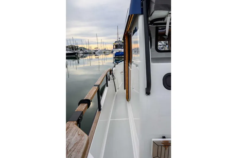  Yacht Photos Pics 2024 Targa 27.2 boat docked at marina, showcasing sleek design and wooden railings.