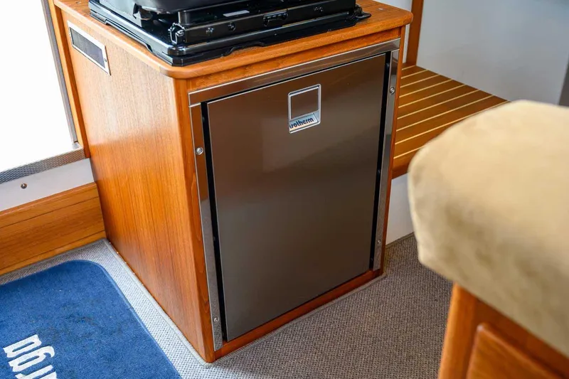  Yacht Photos Pics 2024 Targa 27.2 interior with compact fridge and wooden cabinetry.