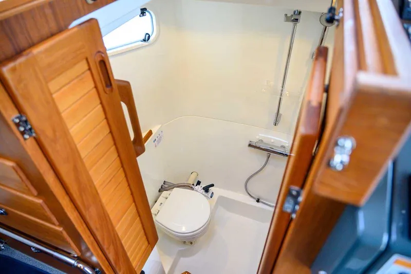  Yacht Photos Pics 2024 Targa 27.2 boat bathroom with wooden door and compact shower area.