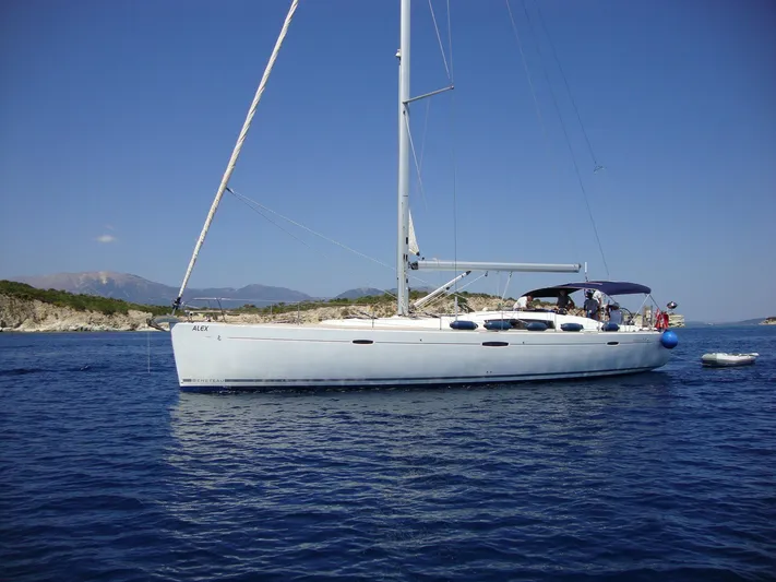  Yacht Photos Pics 2009 Beneteau Oceanis 54 sailboat on calm blue sea near rocky coastline.