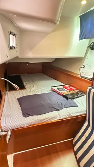  Yacht Photos Pics Cozy cabin interior of 2010 Beneteau Oceanis 50 sailboat with striped chair and reading materials.