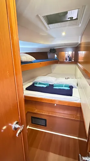  Yacht Photos Pics Cozy cabin interior of 2010 Beneteau Oceanis 50 sailboat with wooden finish and bedding.