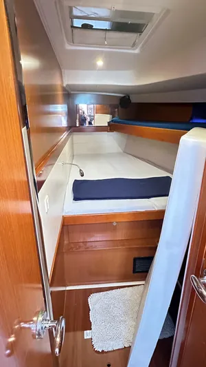  Yacht Photos Pics Cozy cabin interior of 2010 Beneteau Oceanis 50 sailboat with wooden finish and bedding.