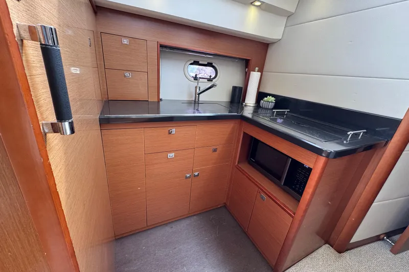  Yacht Photos Pics Compact kitchen area in a 2014 Prestige 400 yacht with modern amenities and wood cabinetry.