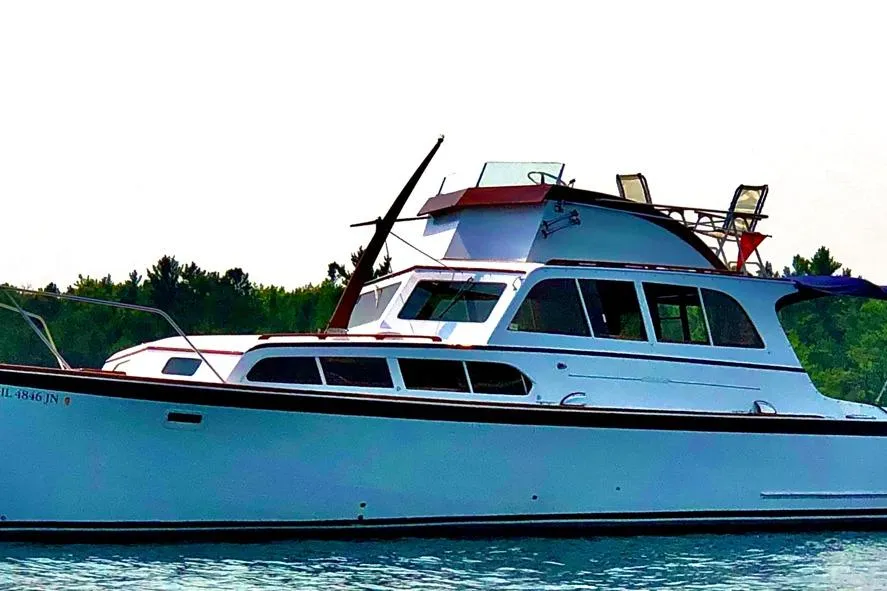 1964 Pacemaker 36 Sportfisherman boat on water, side view, with trees in background.