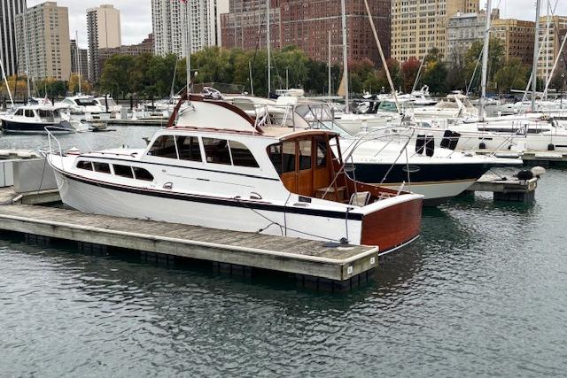 1964 Pacemaker 36 Sportfisherman docked in a marina with cityscape background.