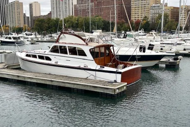 1964 Pacemaker 36 Sportfisherman docked in a marina with cityscape background.