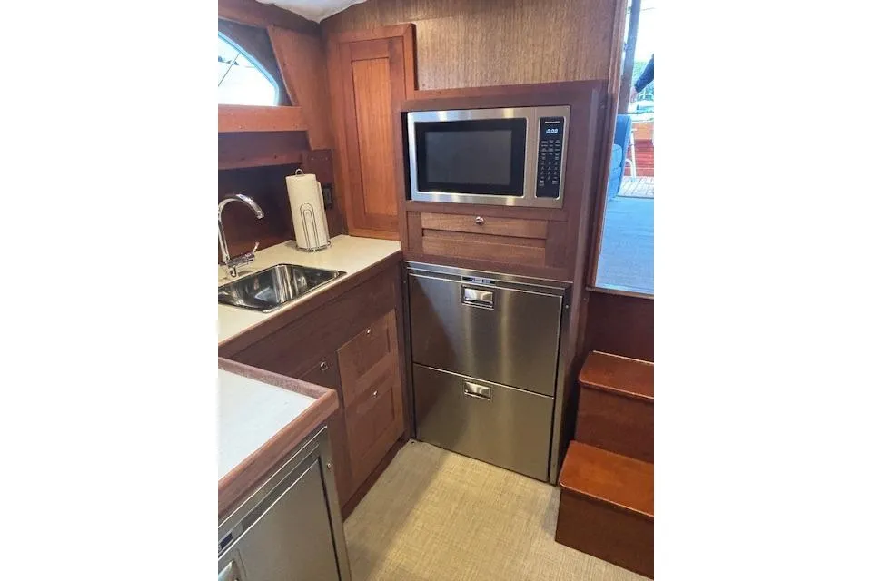 1964 Pacemaker 36 Sportfisherman galley with microwave, sink, and wooden cabinetry.