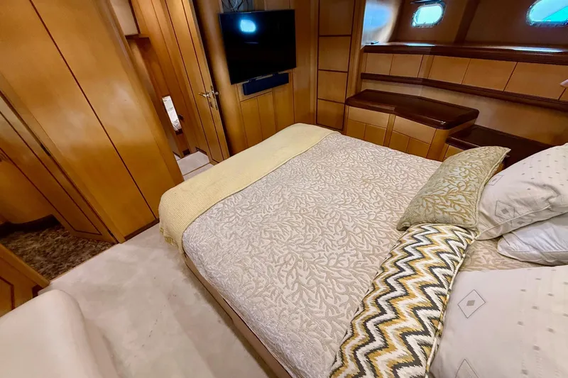 Olivia K Yacht Photos Pics Luxurious bedroom interior of 2005 Mangusta 92 yacht with elegant wood paneling and cozy bedding.