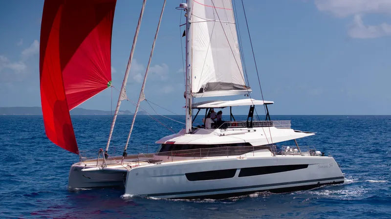  Yacht Photos Pics 2020 Fountaine Pajot Samana 59 catamaran sailing with red spinnaker on open sea.