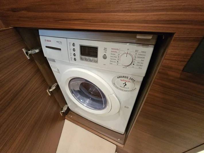  Yacht Photos Pics Washing machine in a 2013 Princess 52 Flybridge yacht, integrated into wooden cabinetry.